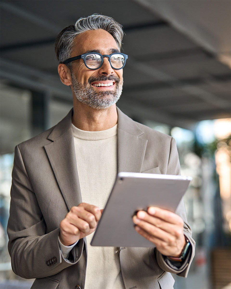 Smiling executive holding a tablet, preparing for a private group training session in a modern business setting