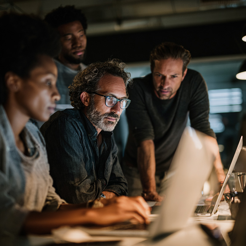 Professionals at different career stages collaborating in a modern tech training environment, representing new hires, junior developers, and analysts preparing for mainframe roles.