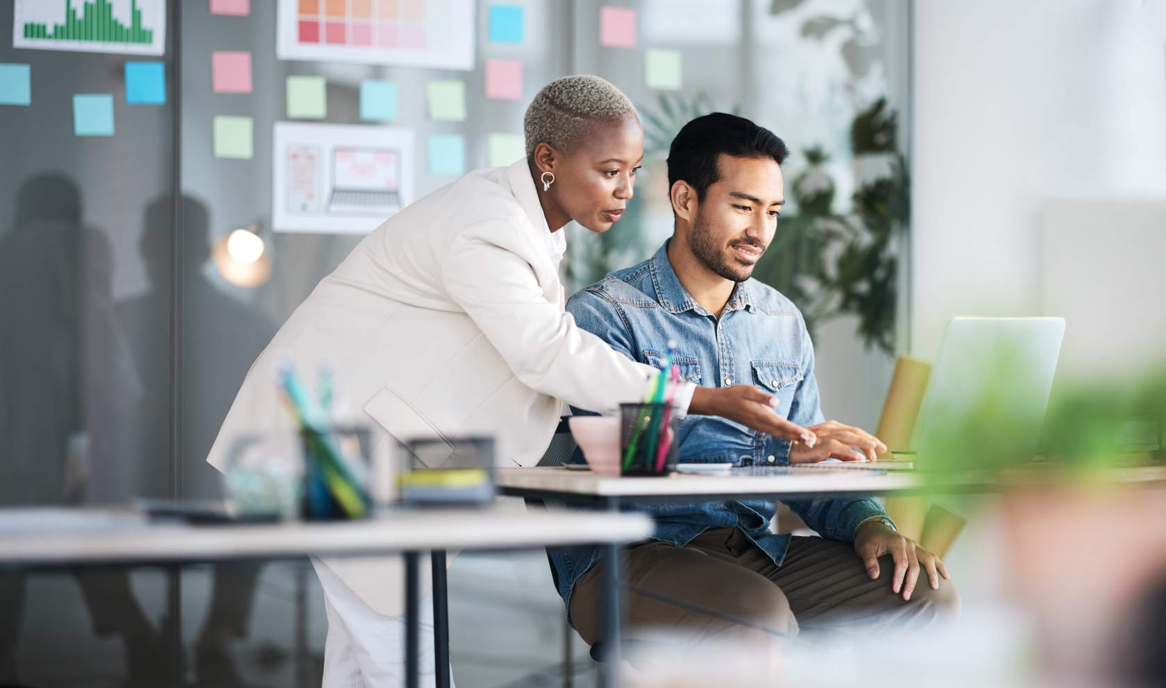 Woman guiding a colleague at a desk, illustrating LearnQuest’s tailored learning solutions in content development.